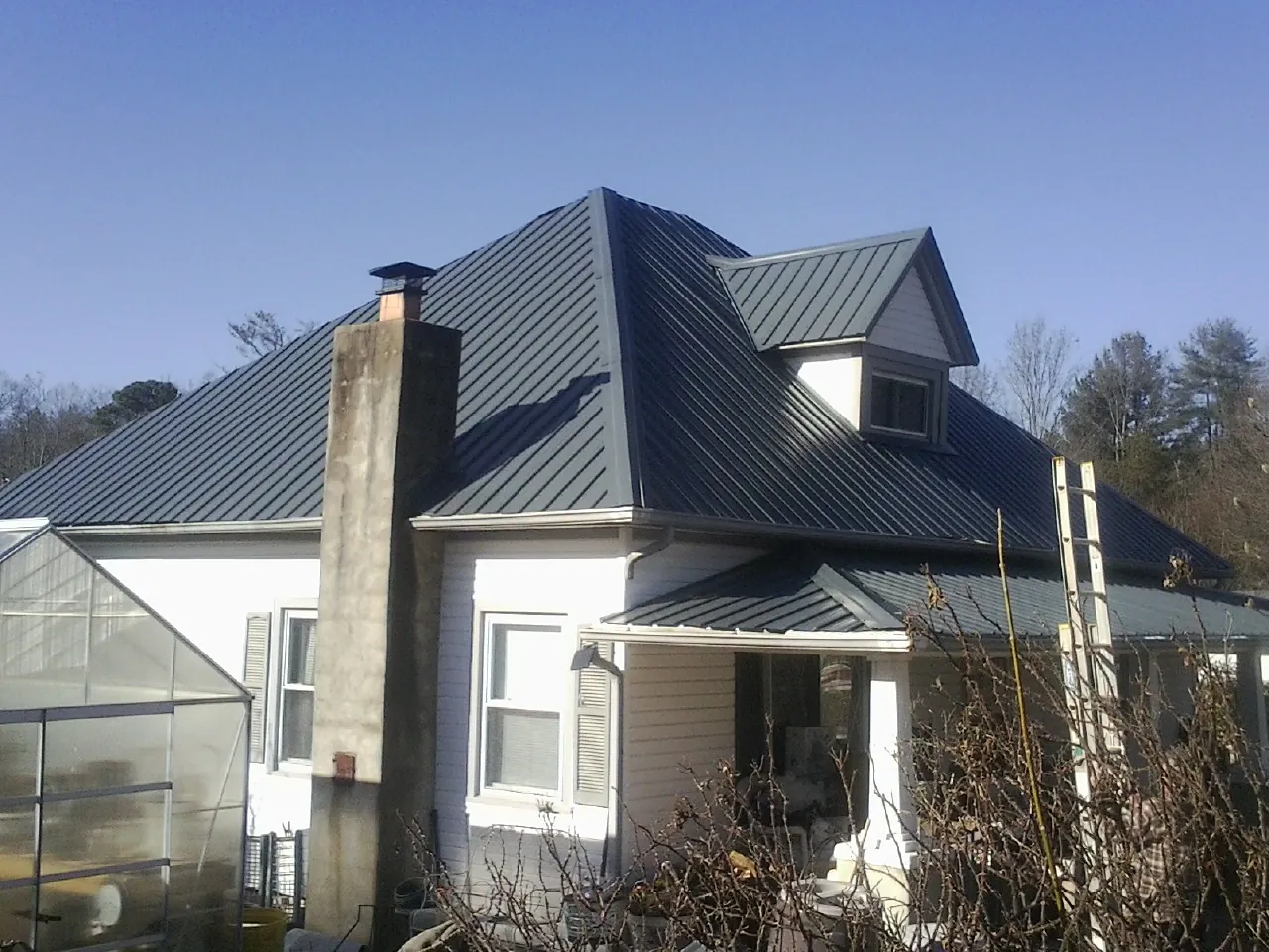 Dark blue standing seam metal roof on a white farmhouse with dormer — Slate & Tile Roof Repair by Roofing Brothers in Valley Head