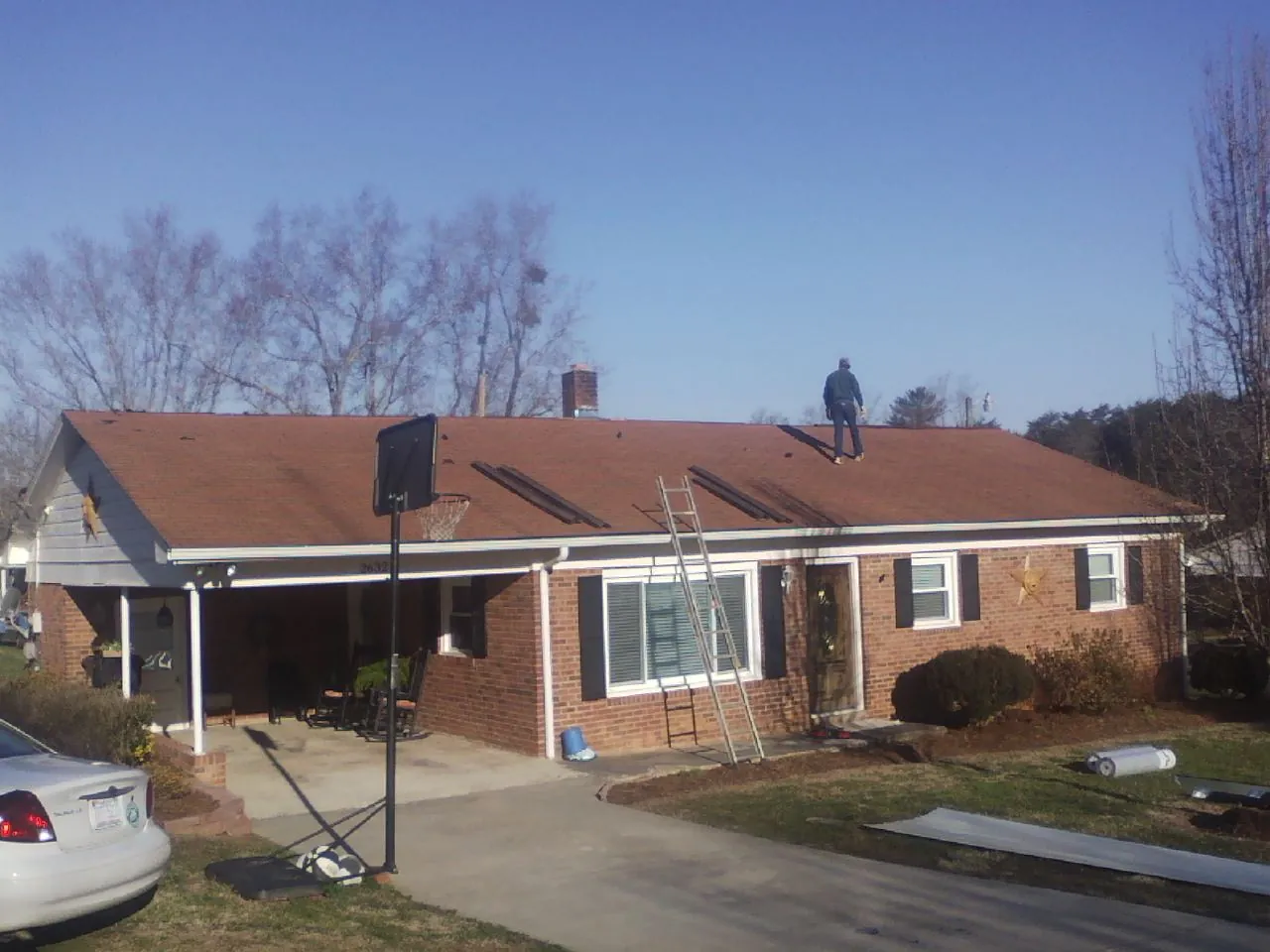 Roofer stripping a shingle roof on a brick ranch before metal panels in Valley Head