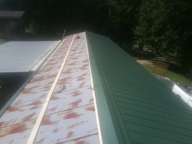 Old rusted panels beside newly installed green metal roofing — Wind Damage Roof Repair by Roofing Brothers in Valley Head