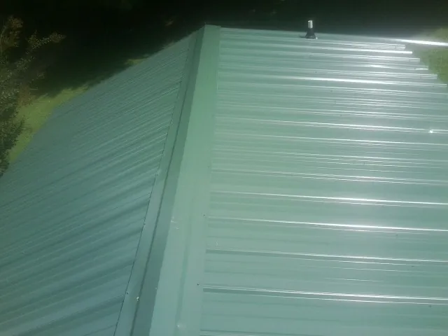 New green metal panels meeting at the ridge of a roof — Flat Roof Repair work by our crew in Valley Head