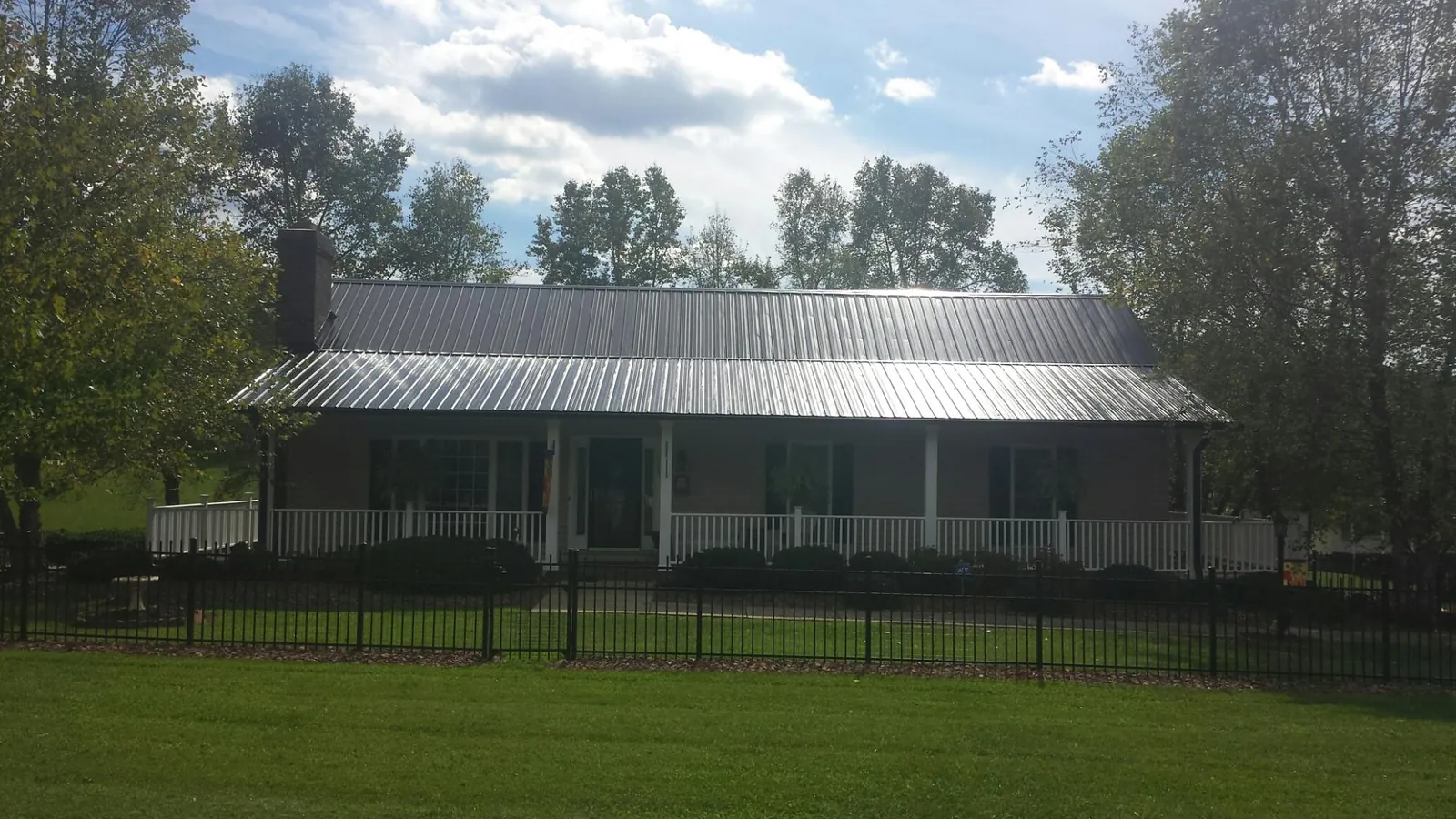 Gray metal roof on a brick ranch with a full width front porch — Gutter Guard Installation work by our crew in Valley Head