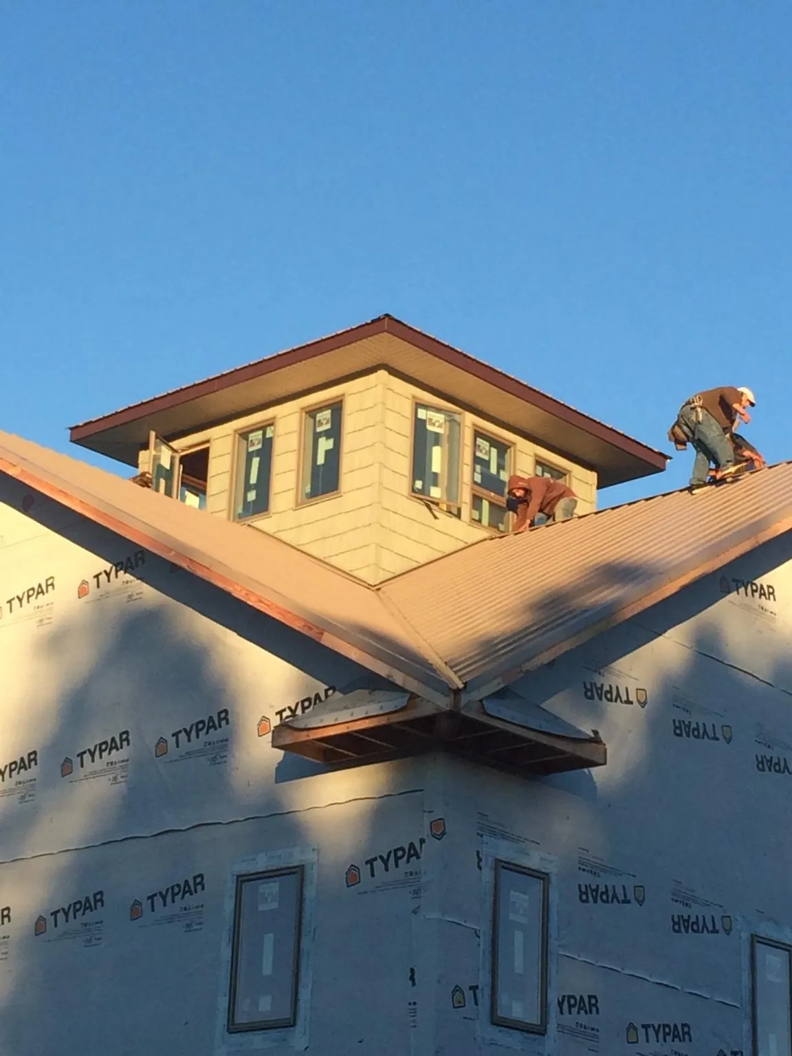 Roofers working around a rooftop cupola on a new metal roof at sunset — Roof Waterproofing in Valley Head by Roofing Brothers